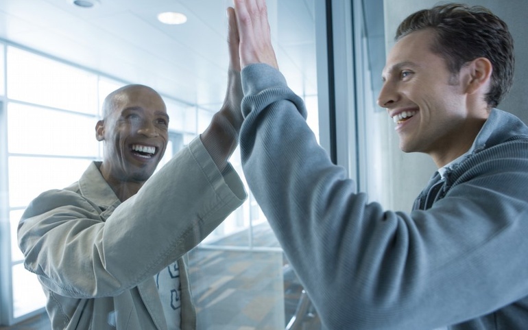 To menn samarbeider på hver sin side av glassvegg