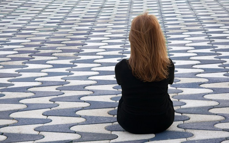 Ung person som sitter med ryggen til kamera, tankefull